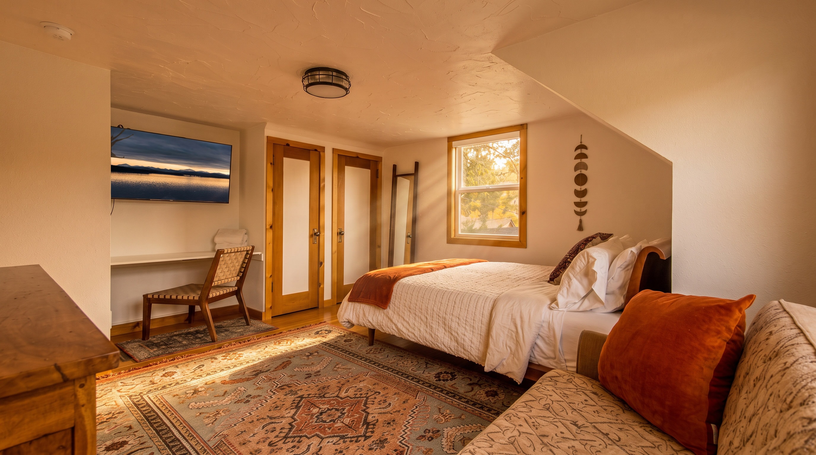 Upstairs Bedroom 1 — wide view with TV, Persian rug, and forest window