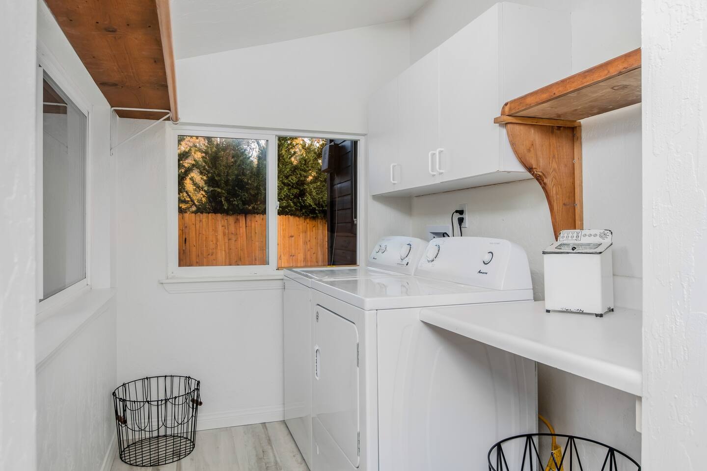 Laundry room with full-size washer and dryer, white cabinetry, and wood beam ceiling
