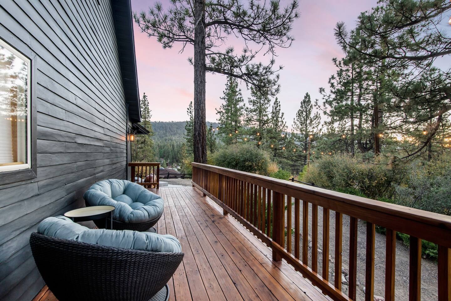 Side deck with blue papasan chairs and forest view at sunset