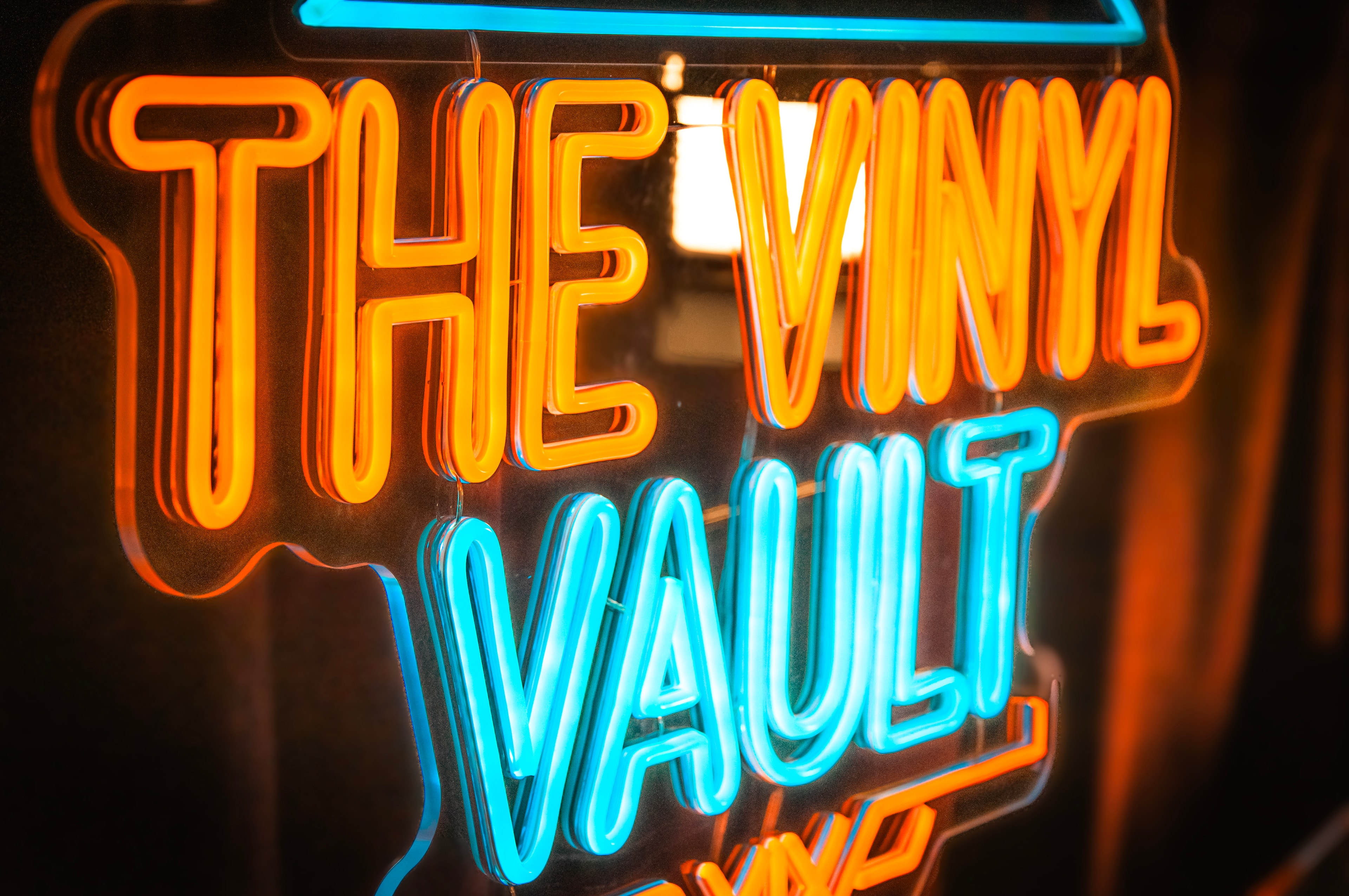 The Vinyl Vault neon sign close-up in orange and cyan