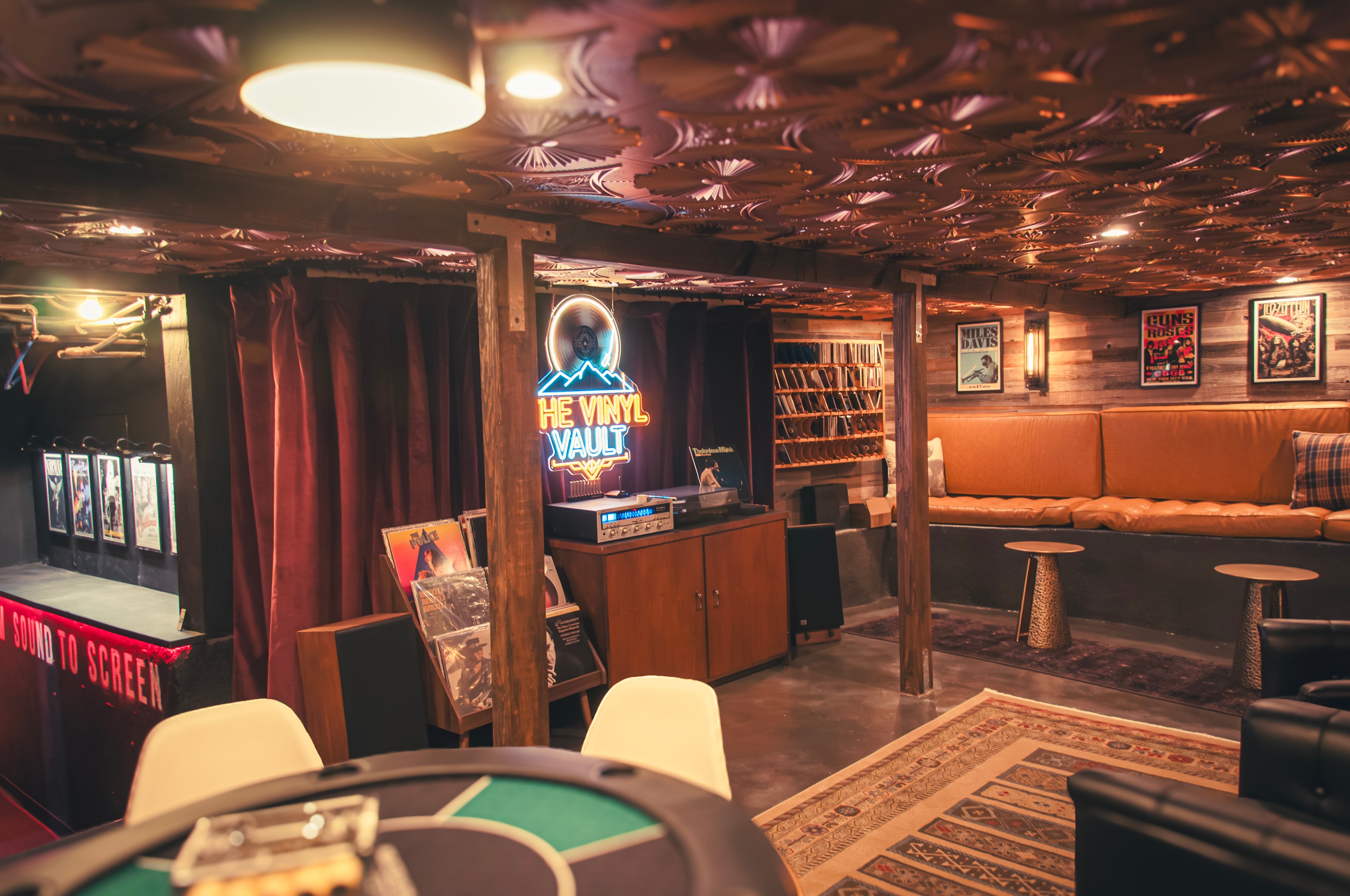 The Vinyl Vault — wide view with neon sign, record shelves, and poker table